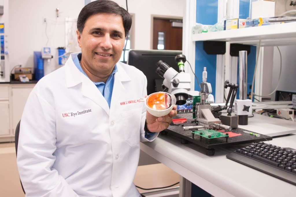 Image of Mark Humayun, MD, PhD of the University of California in the lab holding a stem cell therapy for dry-age macular degeneration.